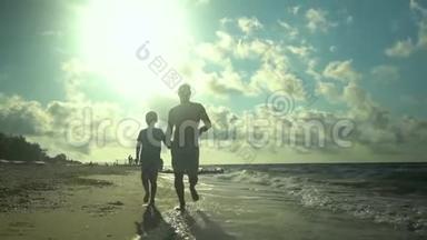一位年轻的父亲和他的儿子沿着海滨跑步。 阳光灿烂. 他们会说话。 家庭幸福。 信托基金